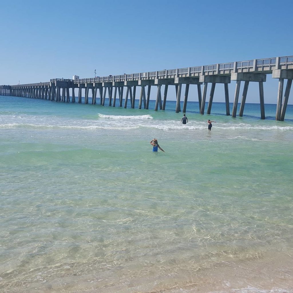 view of the clear water and pier from the beach