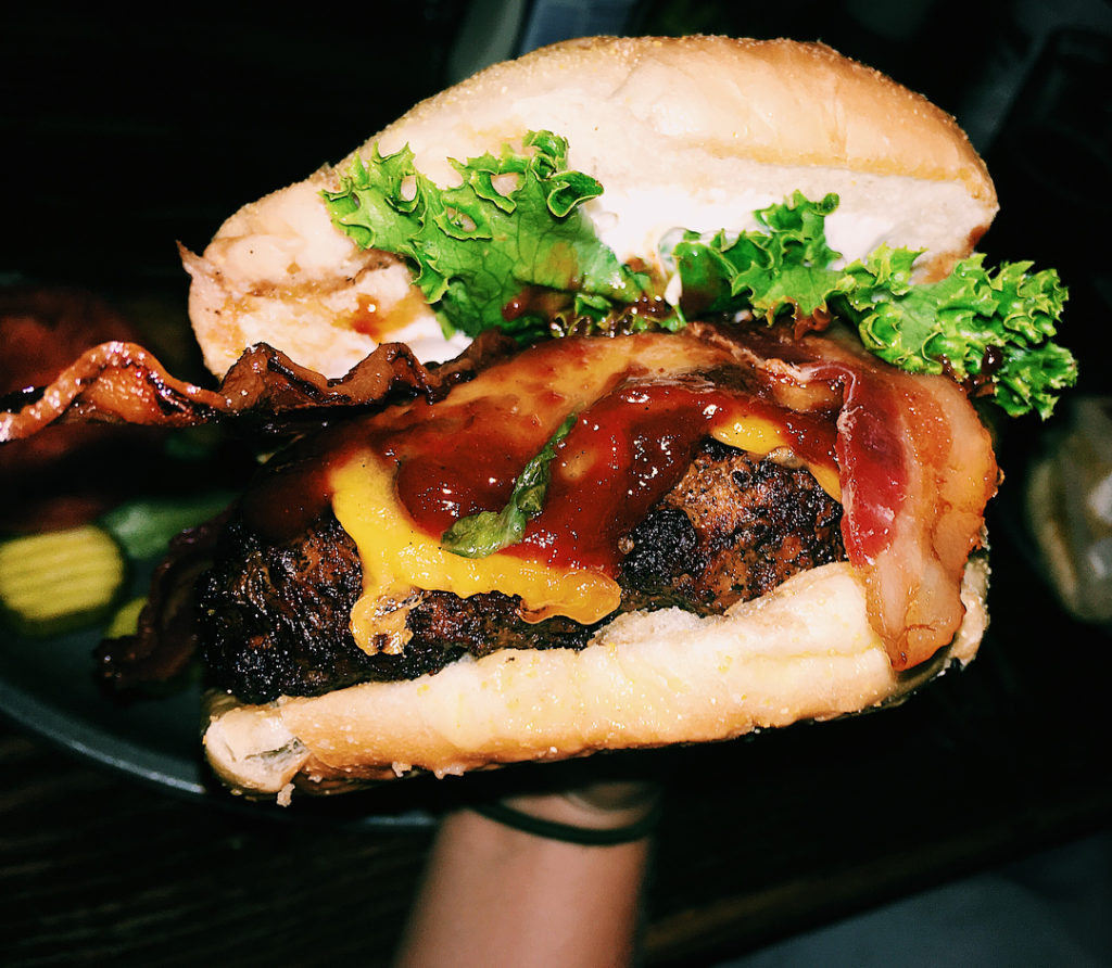 someone holding a meaty bacon burger from McGuire's Irish Pub in Pensacola Florida