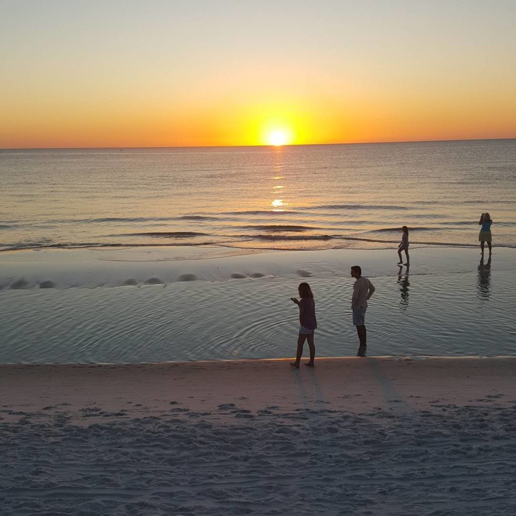 a couple of people walking along the shoreline during sunset at T.H Stone Memorial St. Joseph Peninsula State Park