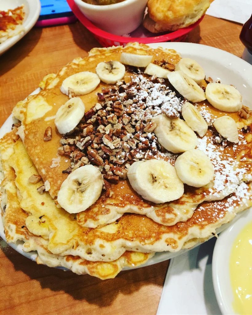 a stack of pancakes with pecans and bananas on top