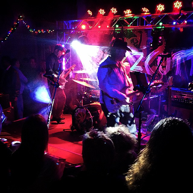 band preforming on stage with blue, purple, and pink lights at Sandshaker