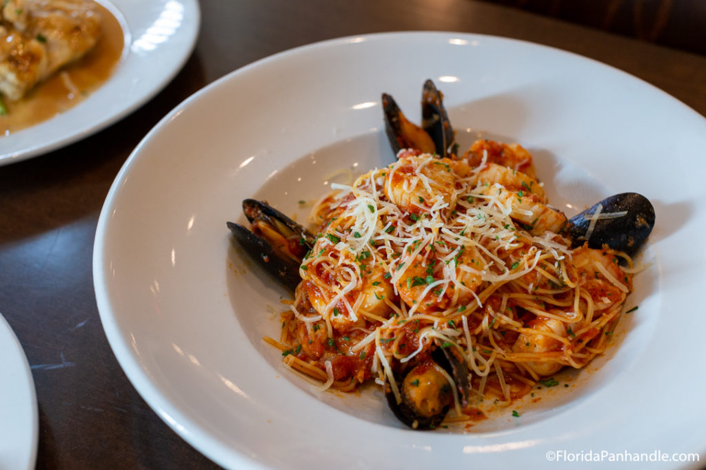 a plate of angle hair spaghetti, mussels and shrimp with shredded cheese on top at Saltwater Grille