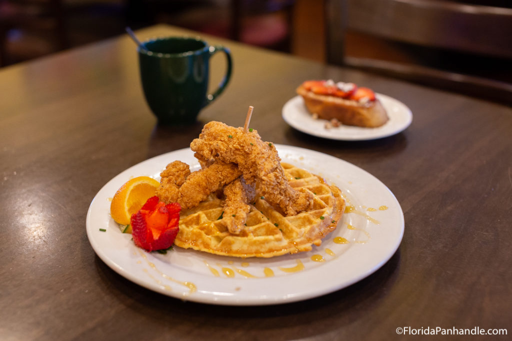 chicken and waffles with an orange slice and a rose shaped strawberry on the side at Andy’s Flour Power