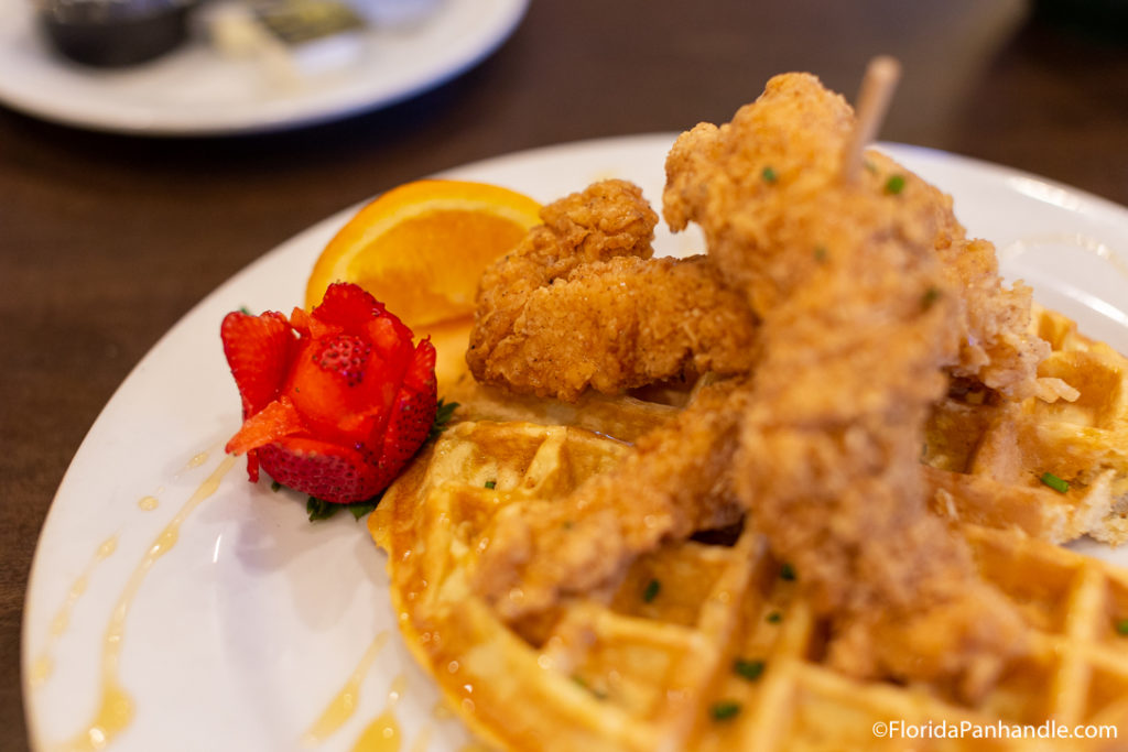 plate of fried chicken and waffles with a strawberry on the side carved into a flower at Andy's Flour Power