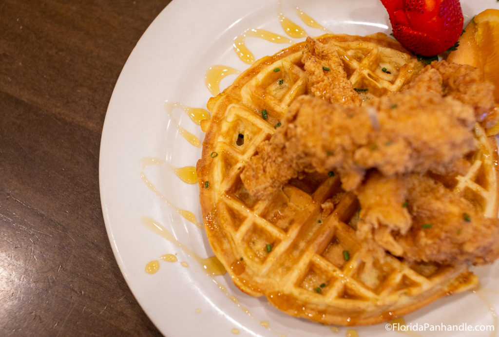 one waffle with fried chicken on top next to red berry at andys flour power