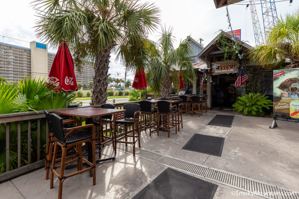 outside front patio of HammerHead Fred's with high top table and chairs and palm trees in Panama City Beach
