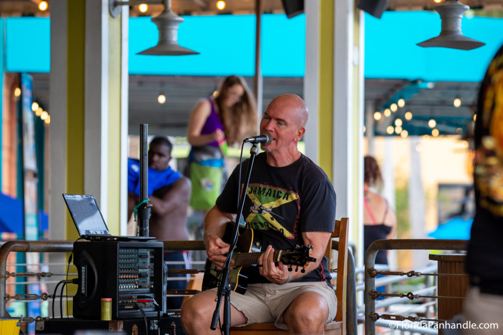 man on stage playing the guitar and singing into a microphone in Panama City Beach 