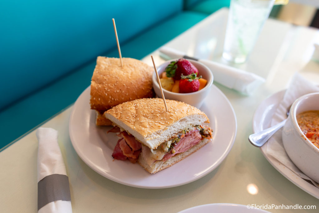 a sandwich cut in half with a side of assorted fruit, 790 Destin