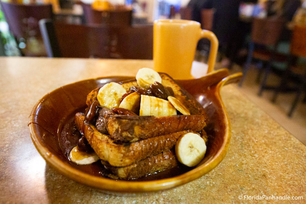 a plate of french toast with bananas and chocolate syrup 