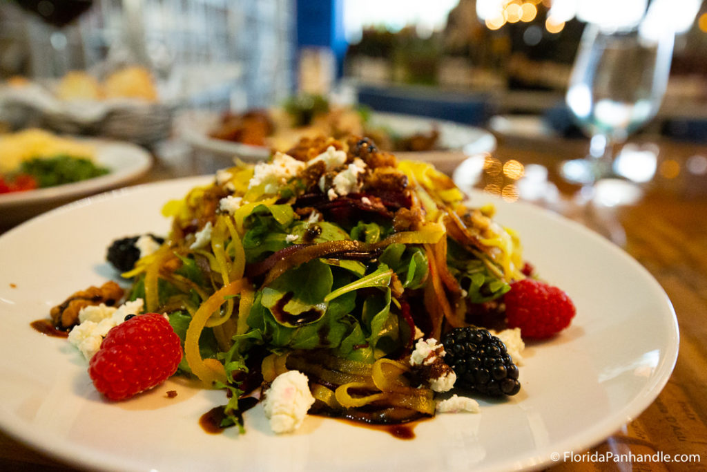 a salad with blackberries and raspberries on top and feta cheese