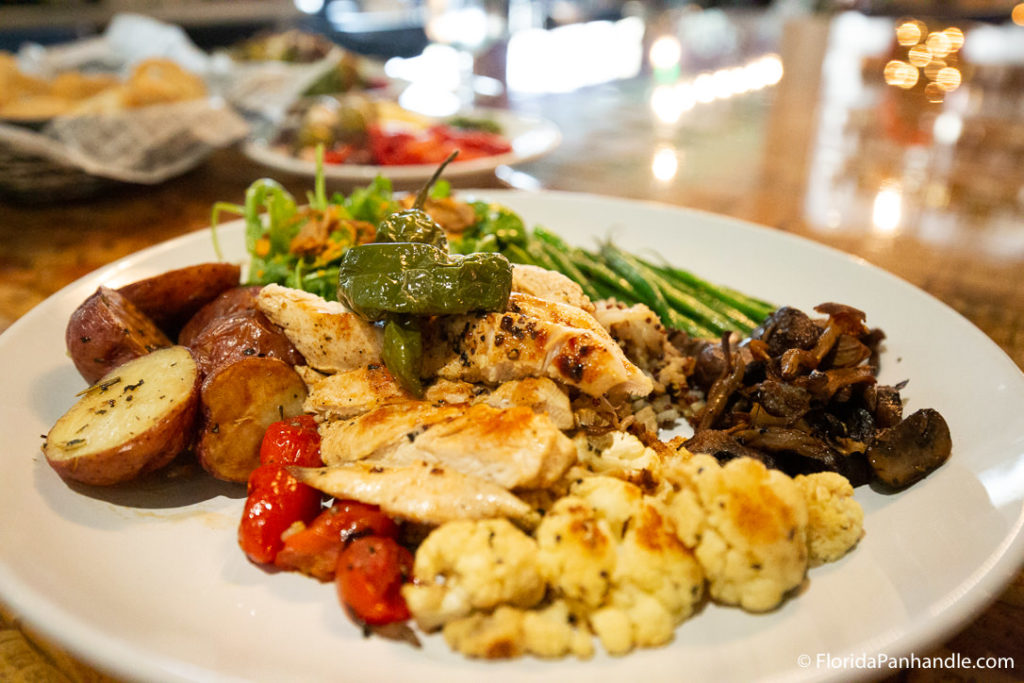 cauliflower, chicken, tomatoes, potatoes, and green beans on top of plate at vintij food and wine, a fine dining establishment in destin, fl