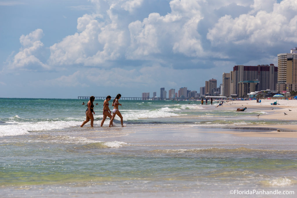 three girls walking up to the beach from the water on a sunny day, beach day