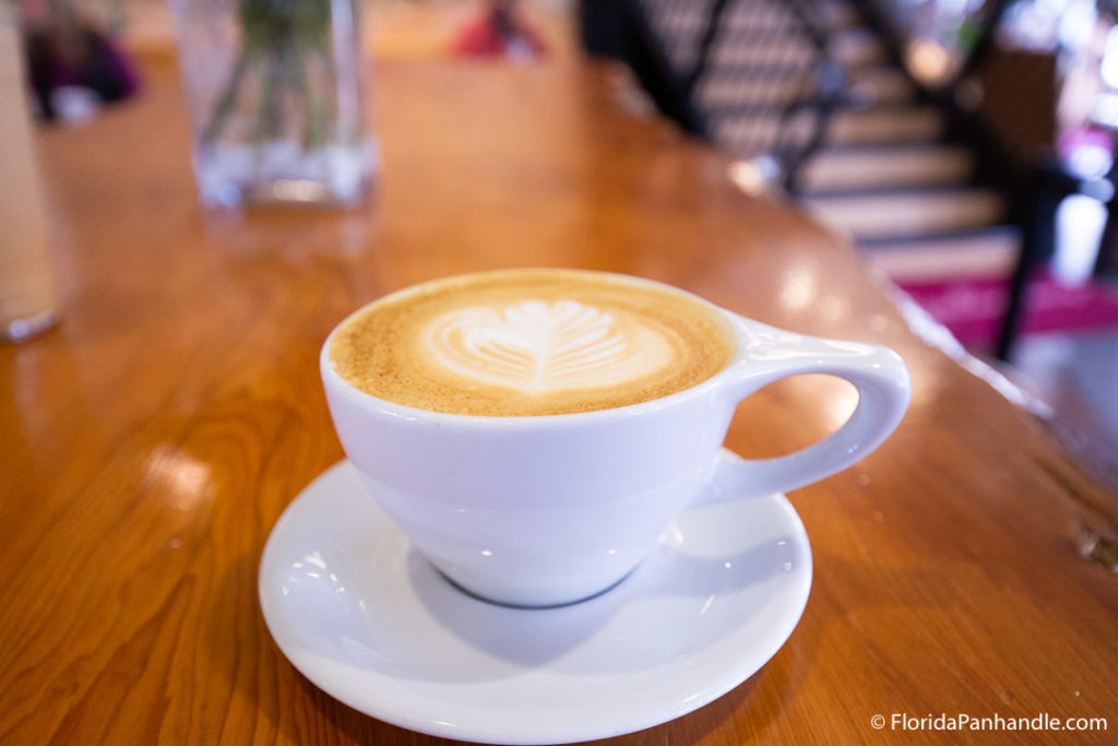 a white mug with coffee and milk foam on top in the shape of a leaf at Bodacious Brew