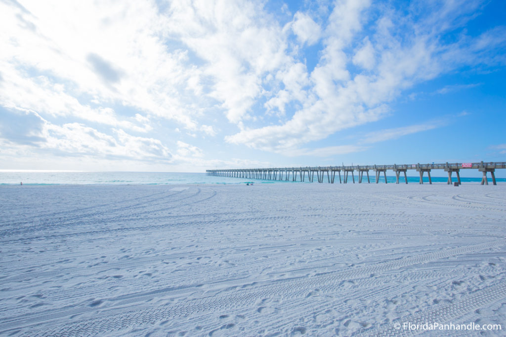 beach sand with blue skies and emerald waters with pier