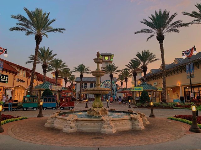 an outdoor water fountain in the middle of a shopping plaza