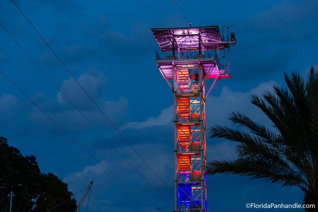 a giant tower lit up in blue, red, and purple at the Harbor Boardwalk 
