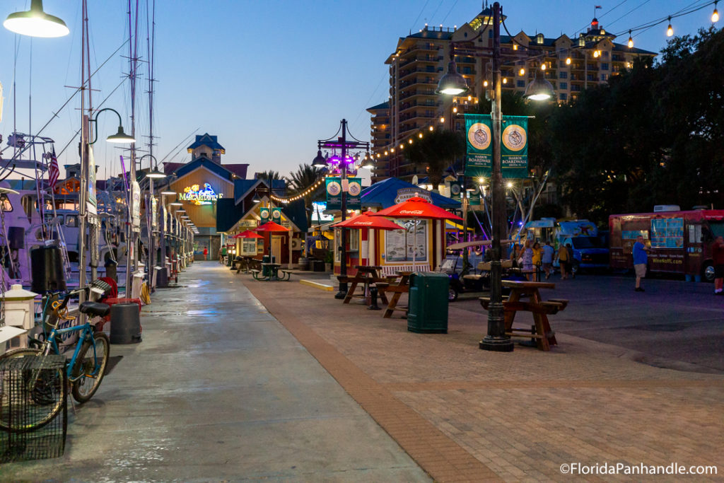 a boardwalk with little shops and hung lights at Destin Harbor Boardwalk in Destin, Florida