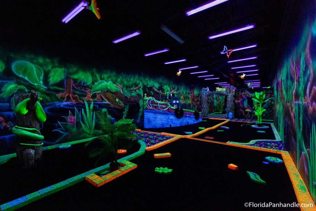a glow in the dark forest themed indoor mini golf at Rainforest Black Light Golf & Arcade