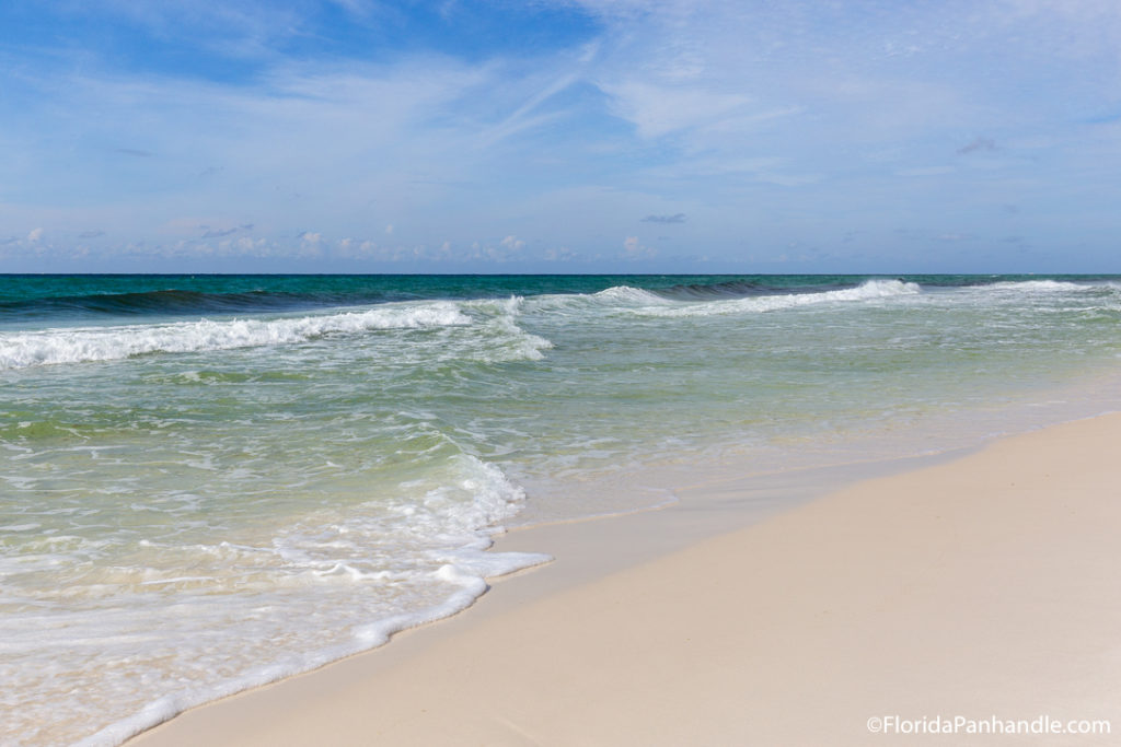 waves washing up on the beach on a sunny day with blue skies at Henderson Beach destin free