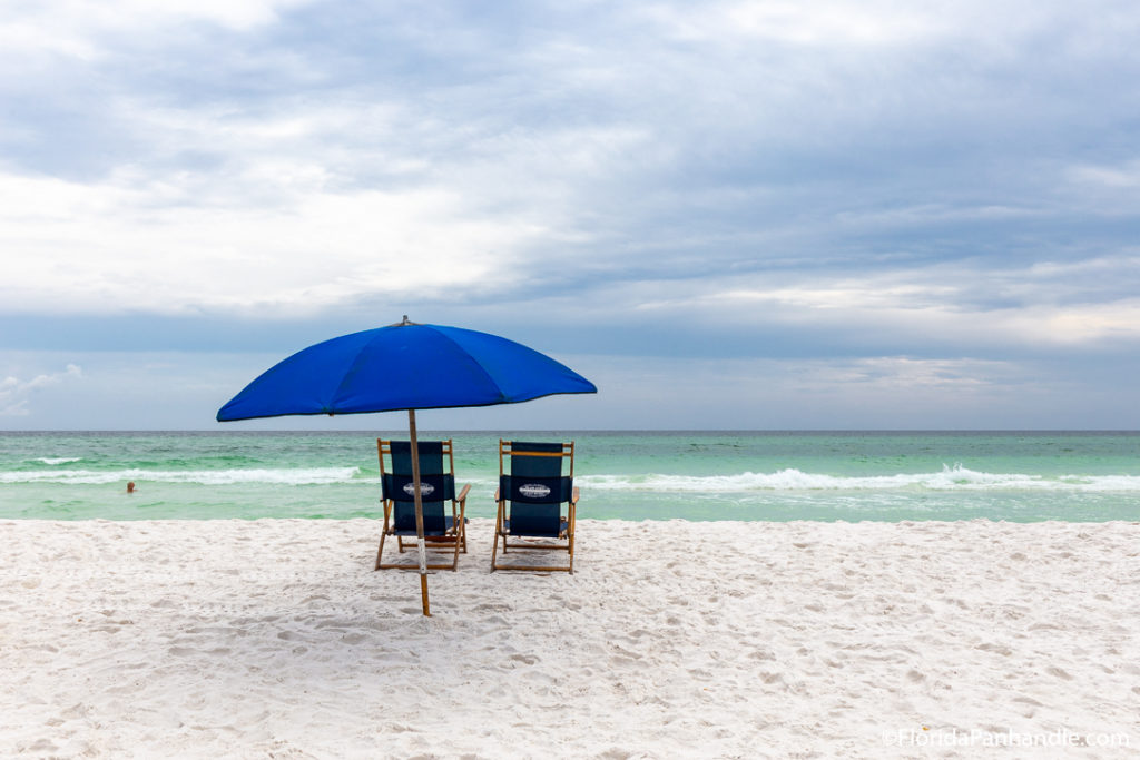 two beach chairs and an umbrella close by the shore on a sunny day in Destin, Florida