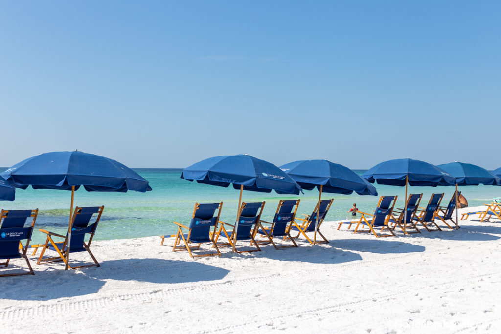 a row of empty beach chairs and umbrellas along the beach at Crystal Beach Park in Florida