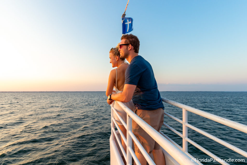 a man and women on a boat watching the sunset together