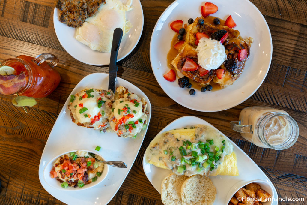 a plate of fruit french toast with whip cream on top, next to a plate of eggs Benedict and egg omelet at Another Broken Egg Cafe  