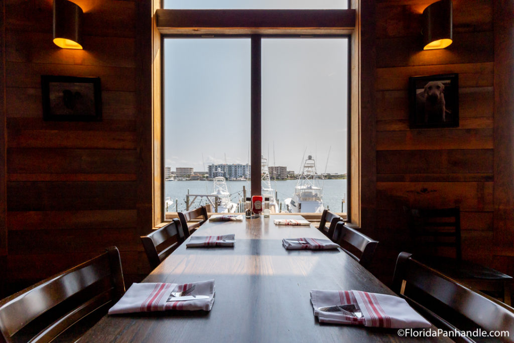 a long dining table with a large window at the end viewing the ocean