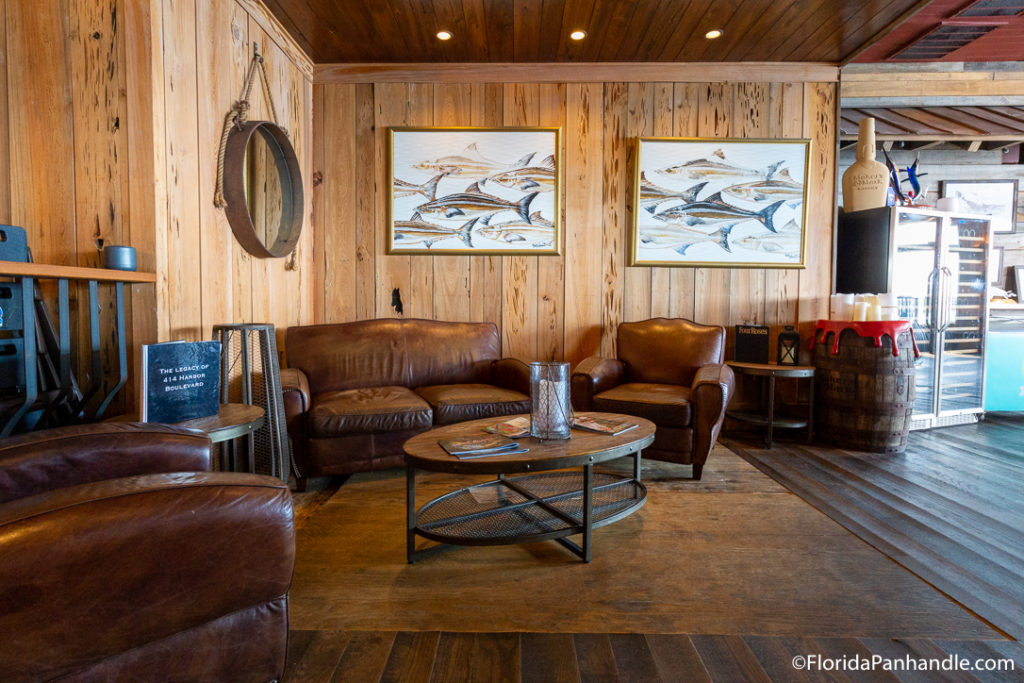 a living room scene with wooden walls and floors with fish paintings on the wall and brown leather couches