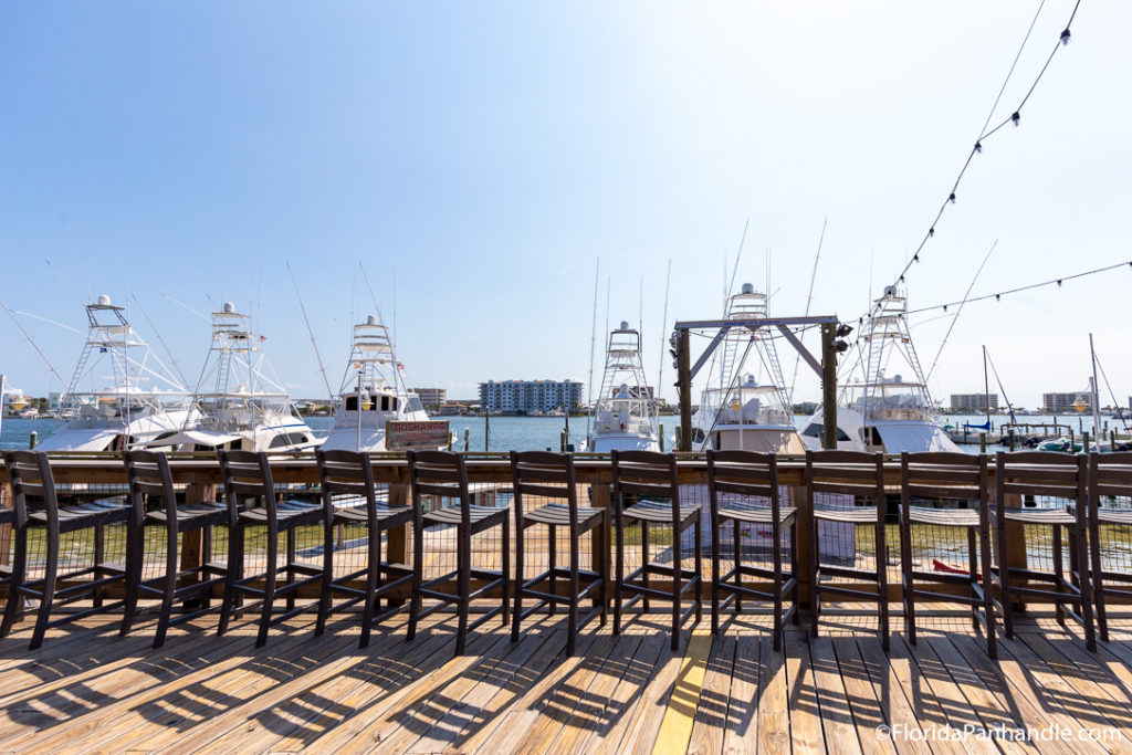 a bar top with bar stools along the side of a deck with views of a boat dock