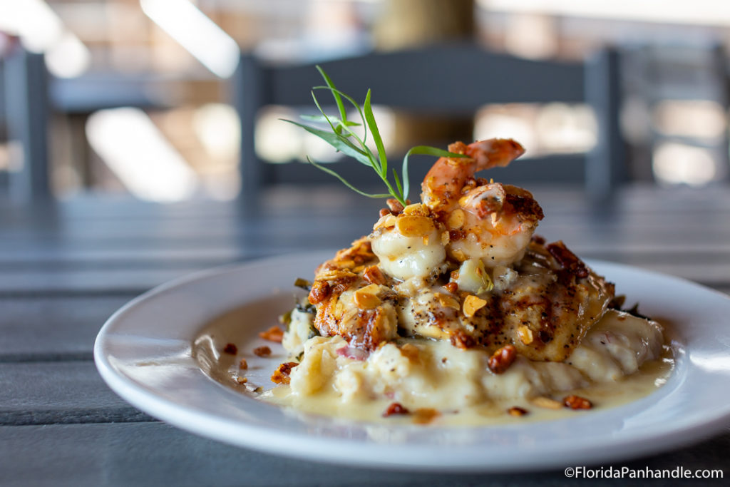 cajun shrimp and grits on a white plate with a leafy green on top for decor