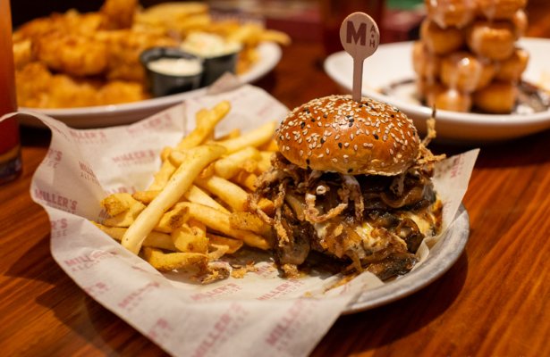 a tall meaty cheesy burger with a side of fries at Millers Ale House in Pensacola, Florida