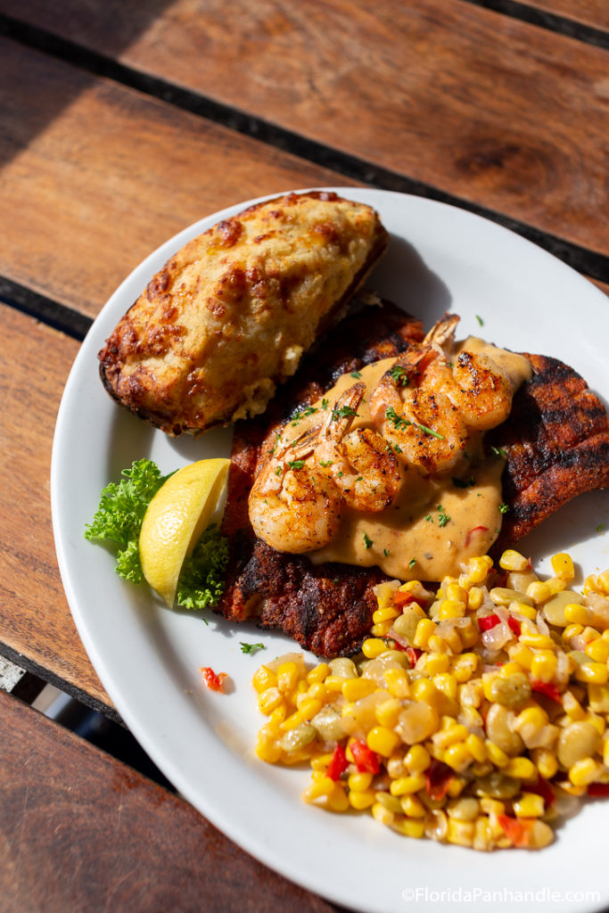 grilled fish with cajun grilled shrimp on top with a side of corn and a baked potato, restaurant, florida