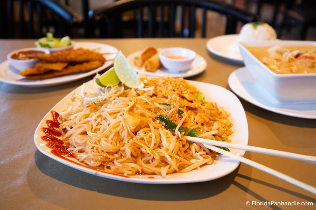 a plate of noodle with lemon wedges on the side and chopsticks