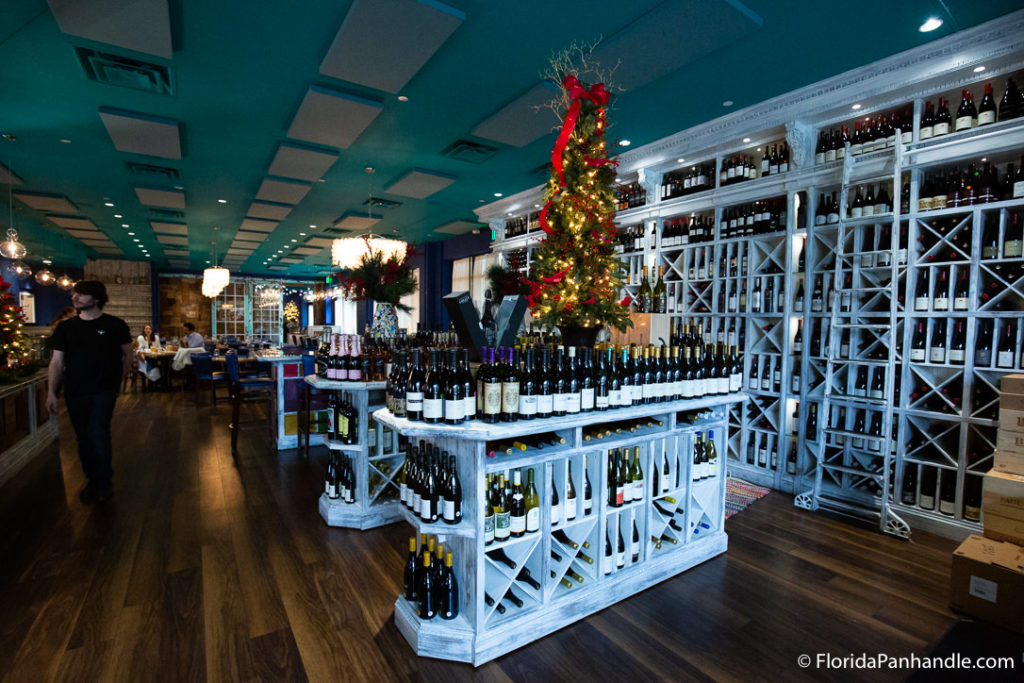 a large wine selling area with wine in multiple shelves with christmas tree in background