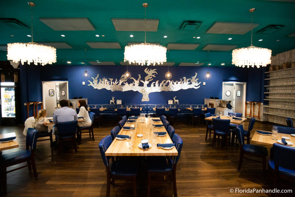 a dining area with turquoise ceilings and a navy blue accent wall with a silver painting of a wide tree