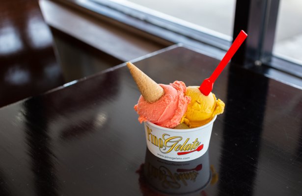 a cup of two different kinds of ice cream scoops -- yellow and pink with a mini cone in it at Pino Gelato Cafe in Destin, Florida