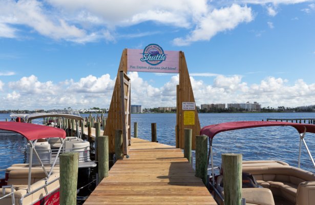 a boardwalk over the water with a pink wooden sign and two boats parked along the side