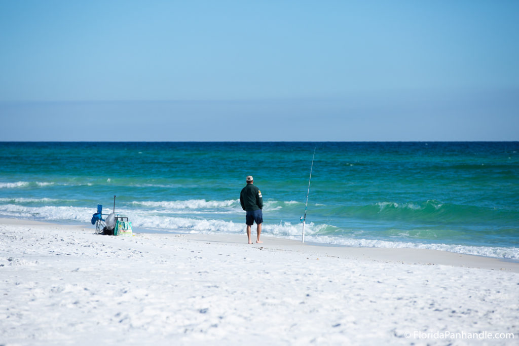 a man fishing at the beach by the shoreline at Opal Beach