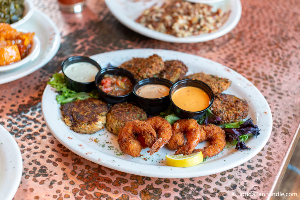 a plate of fried shrimp, and scallops with four different dipping sauces