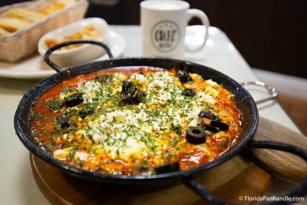 a pasta cooked in a skillet with melted cheese on top and black olives