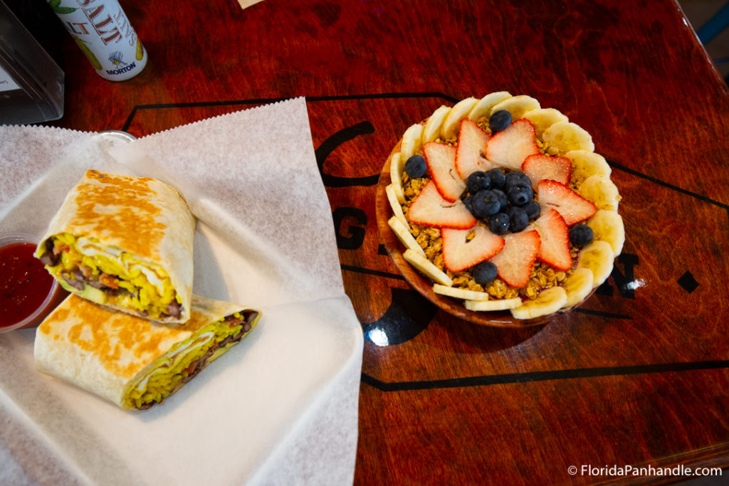 a breakfast wrap with a side of fruit and granola 