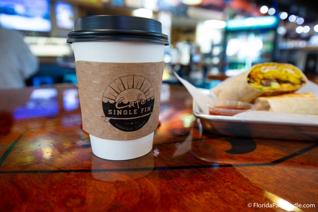 a cup on coffee in a paper cup with a black plastic lid at Cafe Single Fin