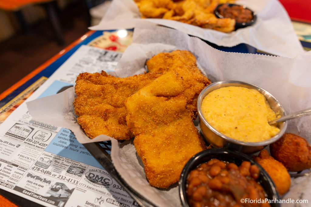 fried fish next to yellow dipping sauce and baked beans