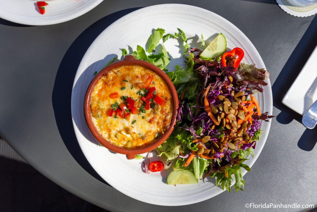 a salad with pumpkin seeds in top and a side of cheese soup