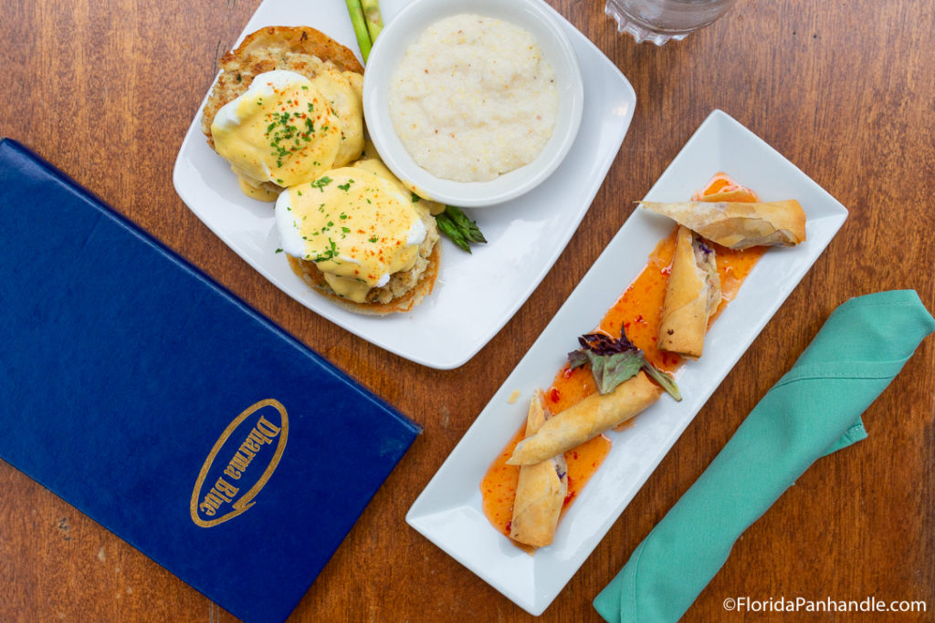 a plate of eggs Benedict with a side bowl of grits and egg rolls at Dharma Blue in Pensacola Beach Florida