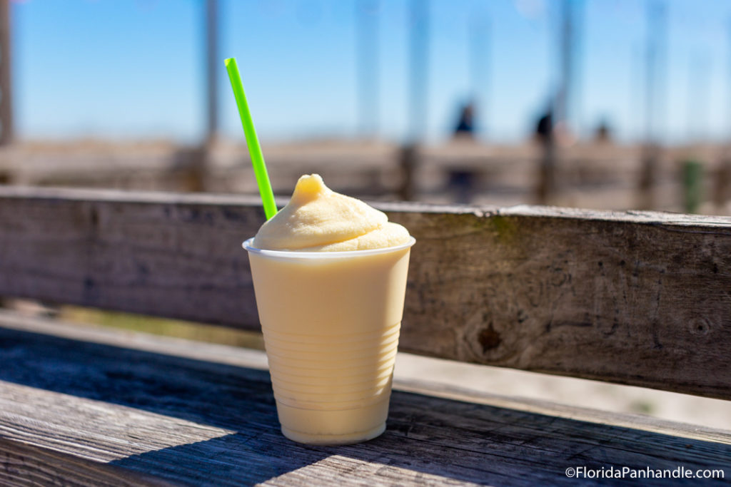 a tan colored smoothie drink in a clear cup with a lime green straw, frozen cocktails