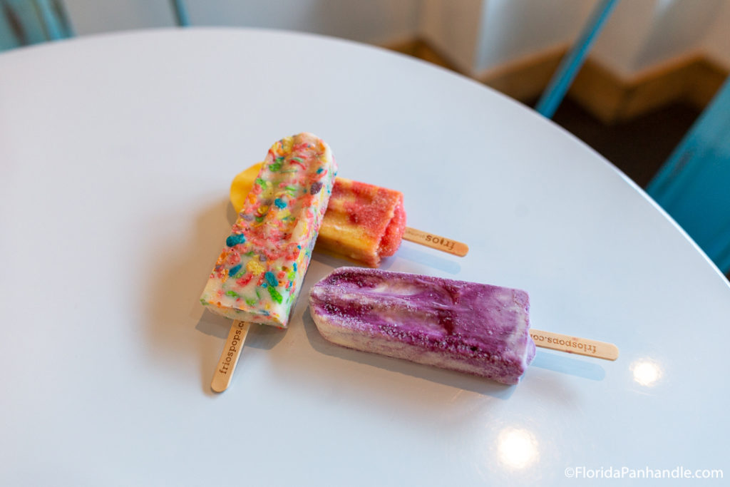 a purple, rainbow and yellow and red popsicles layered on top of each other