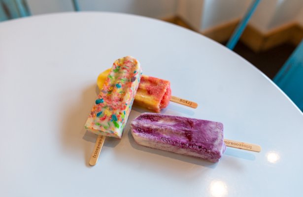 a confetti, purple, red and orange ice pops stacked together on a white table