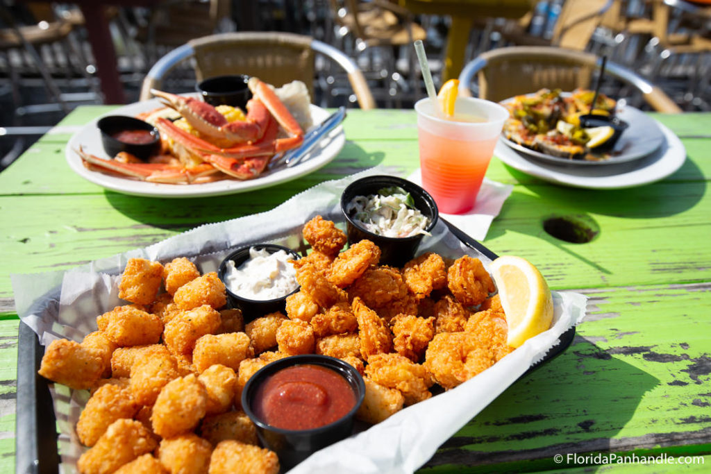 a tray of deep fried shrimp and cheese curds with dipping sauces on the side at Frisky Dolphin Sunset Oyster Bar and Gril
